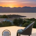 Sunset with armchair, open book and portable lamp beside the edge of the infinity pool