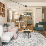 Wohnzimmer mit offener Küche, Eichenregal, rundem Esstisch und weißer Pendelleuchte