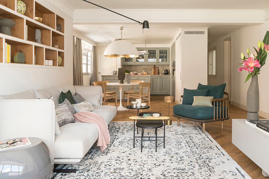 Wohnzimmer mit offener Küche, Eichenregal, rundem Esstisch und weißer Pendelleuchte