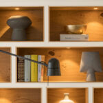 Eingebautes Eichenregal mit warmer Spotbeleuchtung, Keramikvasen, goldener Schale und Büchern