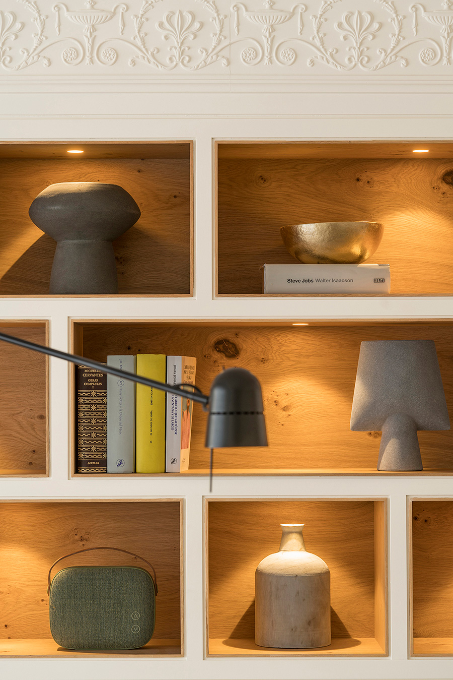Eingebautes Eichenregal mit warmer Spotbeleuchtung, Keramikvasen, goldener Schale und Büchern