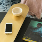 Detail eines Couchtischs mit goldener Messingplatte, Schale aus hellem Stein und Kunstband