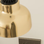 Detail einer Pendelleuchte aus poliertem Messing und metallener Schalterblende mit Schaltern und USB-Steckdose an der Wand