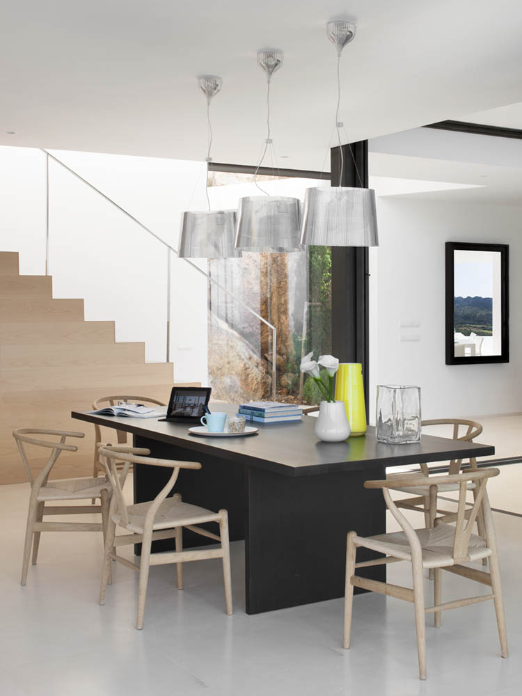Esszimmer mit dunklem Tisch, Holzstühlen und silbernen Leuchten neben der Treppe aus hellem Holz