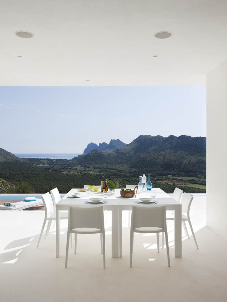 Überdachter Essbereich im Freien mit weißem Tisch und Stühlen, Blick auf Tal, Berge und Meer