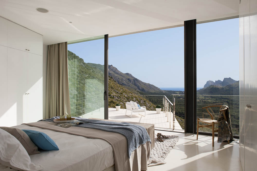 Schlafzimmer mit raumhohem Fenster und Terrasse mit Blick auf Berge und Meer