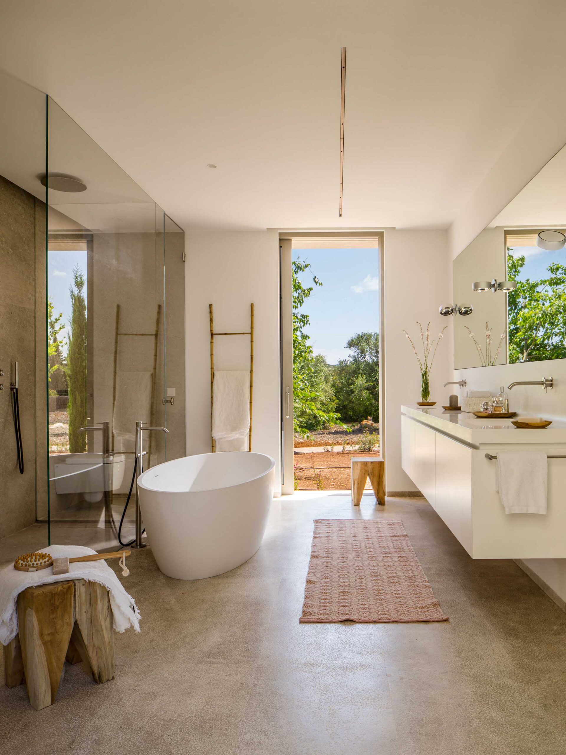 Baño completo con bañera exenta, doble lavabo suspendido, ducha acristalada y ventana alta al jardín