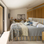 Dormitorio con colcha estampada azul, escritorio de madera, armarios empotrados y balcón con vistas.