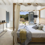 Dormitorio con cama de dosel y gasa, vigas blancas y terraza con vistas al campo