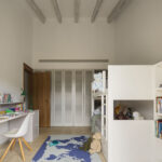 Habitación infantil con litera blanca, escritorio, armario de lamas y alfombra de mapamundi azul