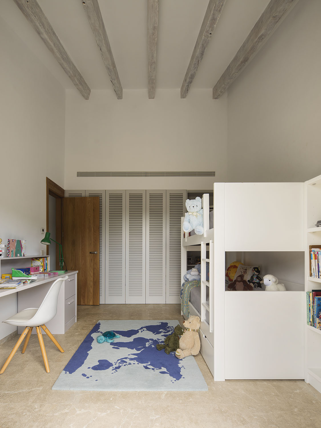 Habitación infantil con litera blanca, escritorio, armario de lamas y alfombra de mapamundi azul