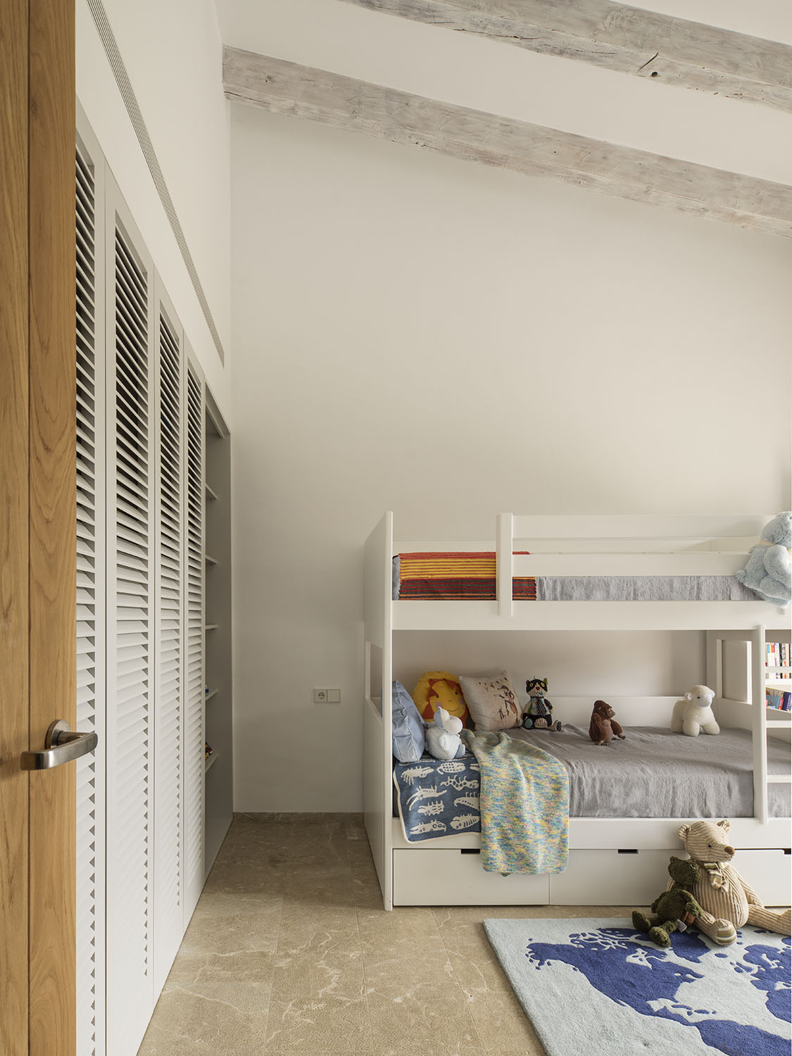 Litera blanca con cajones, armario de lamas y vigas de madera envejecida en dormitorio infantil