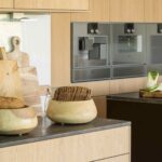 Detalle de encimera con cuencos de madera con pan, tablas de cortar y hornos empotrados