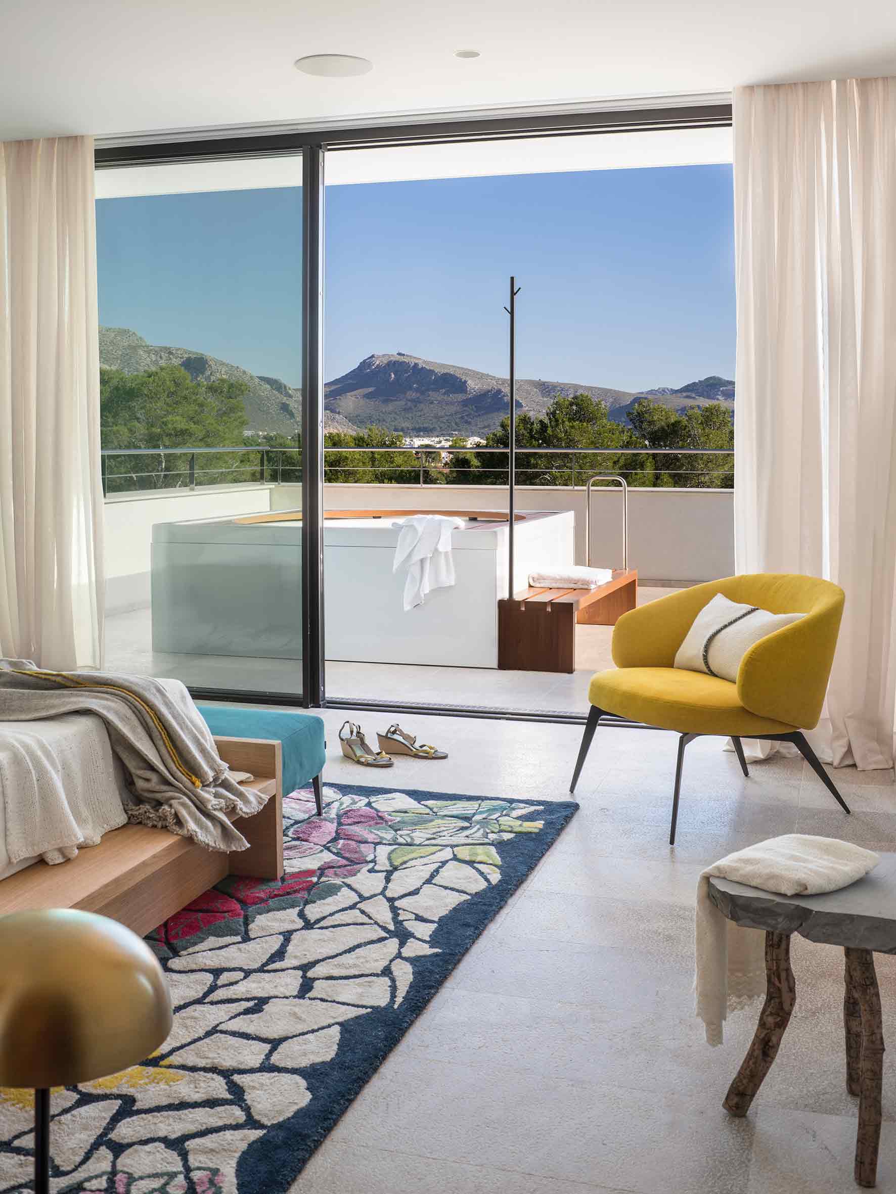 Dormitorio con puerta corredera de cristal a una terraza con jacuzzi y vistas a la montaña