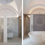 Baño abovedado con ducha de mármol y bañera exenta ante un panel de azulejos geométricos