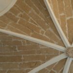 Detalle de bóveda de piedra vista con nervios blancos y clave central ornamentada