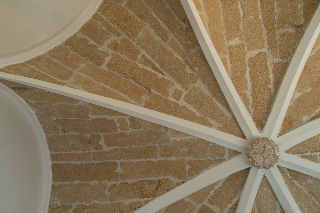 Detalle de bóveda de piedra vista con nervios blancos y clave central ornamentada