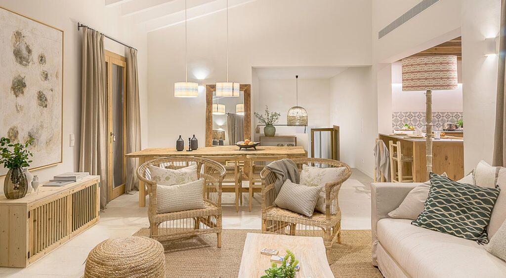 Wohnzimmer mit Korbsesseln, hellem Sofa, Naturfaserteppich und Essgruppe aus Holz im Hintergrund