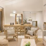 Wohnzimmer mit Korbsesseln, hellem Sofa, Naturfaserteppich und Essgruppe aus Holz im Hintergrund