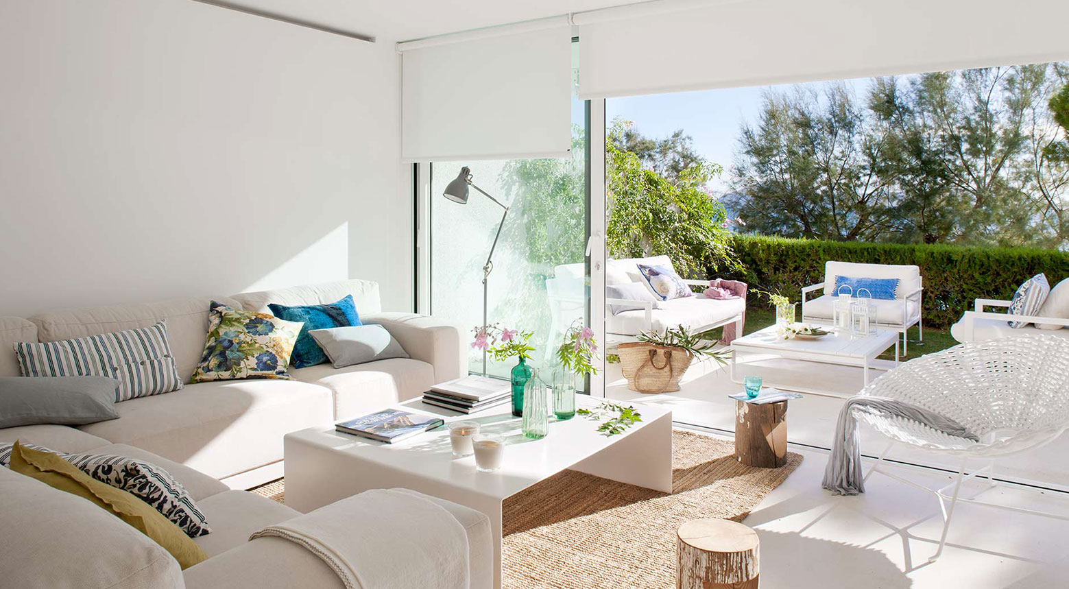 Helles Wohnzimmer mit cremefarbenem Sofa, weißem Tisch und Juteteppich, offen zu Terrasse und Garten