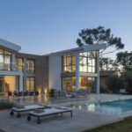 Villa Bonaire al anochecer con fachada blanca y de piedra, grandes ventanales iluminados y piscina