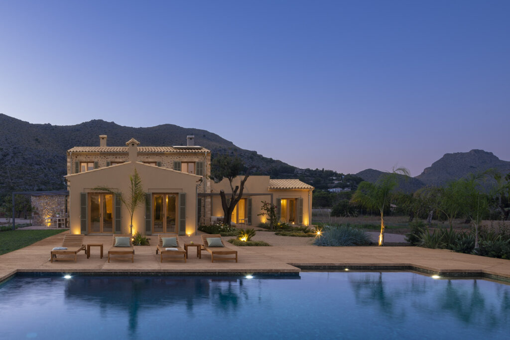 Sa Vinya, casa de campo con piscina, tumbonas y terraza iluminada al anochecer bajo las montañas