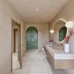 Baño con ducha en nicho arqueado de azulejo verde, paredes beige, doble grifería y espejo orgánico iluminado
