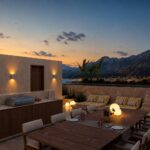 Dachterrasse des Neubauprojekts J23 bei Sonnenuntergang mit Essbereich im Freien, Grill und Bergblick