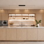 Cocina con isla central de roble claro, encimera de piedra beige, hornos empotrados y estantes iluminados