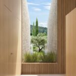 Render of a timber-panelled corridor with a tall window framing an olive tree and cypresses between two stone walls
