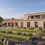 Visualización de la finca de piedra con cubierta de teja, piscina y montañas al fondo