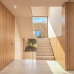Render del vestíbulo de Can Melis con escalera, paneles de madera y luz natural