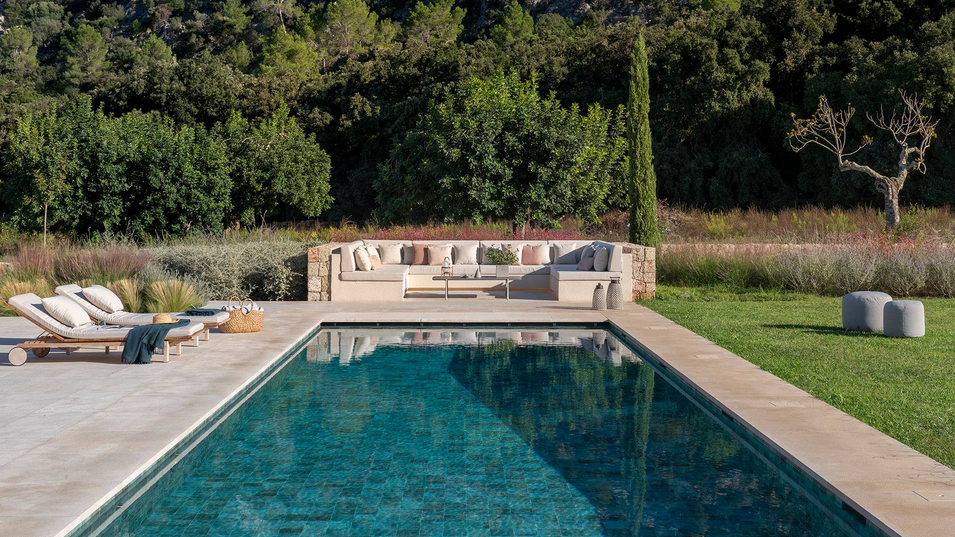 Piscina de azulejo verde con tumbonas, zona de estar exterior de obra y jardín mediterráneo